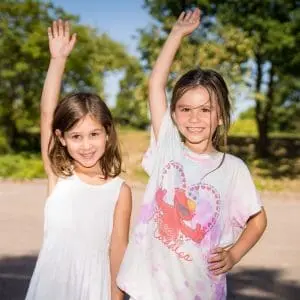 Two girls waving outdoors
